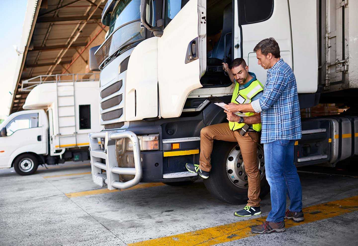 two men discussing papers at a semi truck