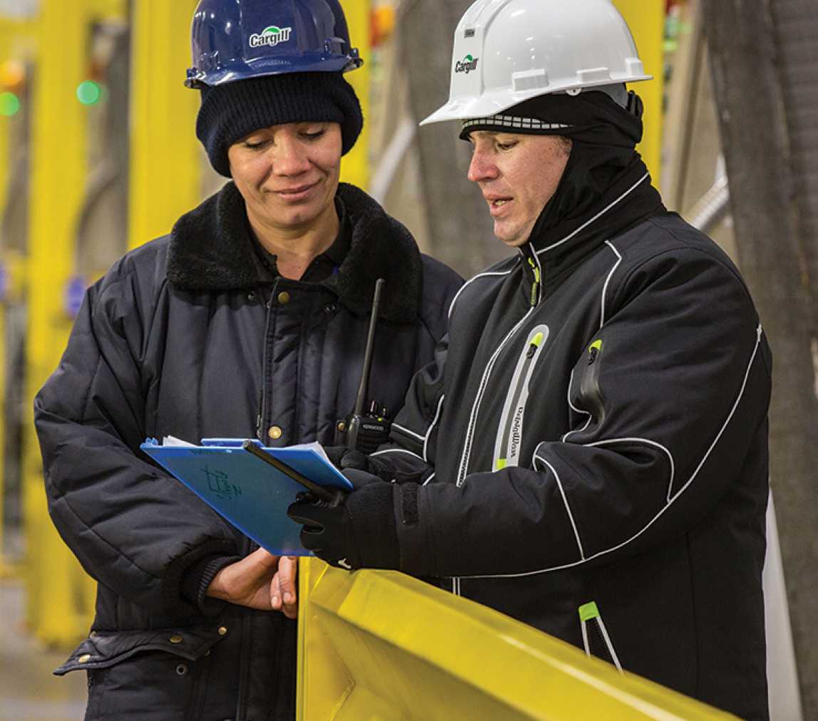 two people in a factory in hard hats